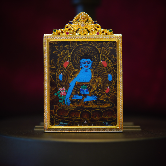 Hand-painted black gold Medicine Buddha pendant with intricate sapphire-blue design, featuring floral gold leaf details and Tibetan carvings.