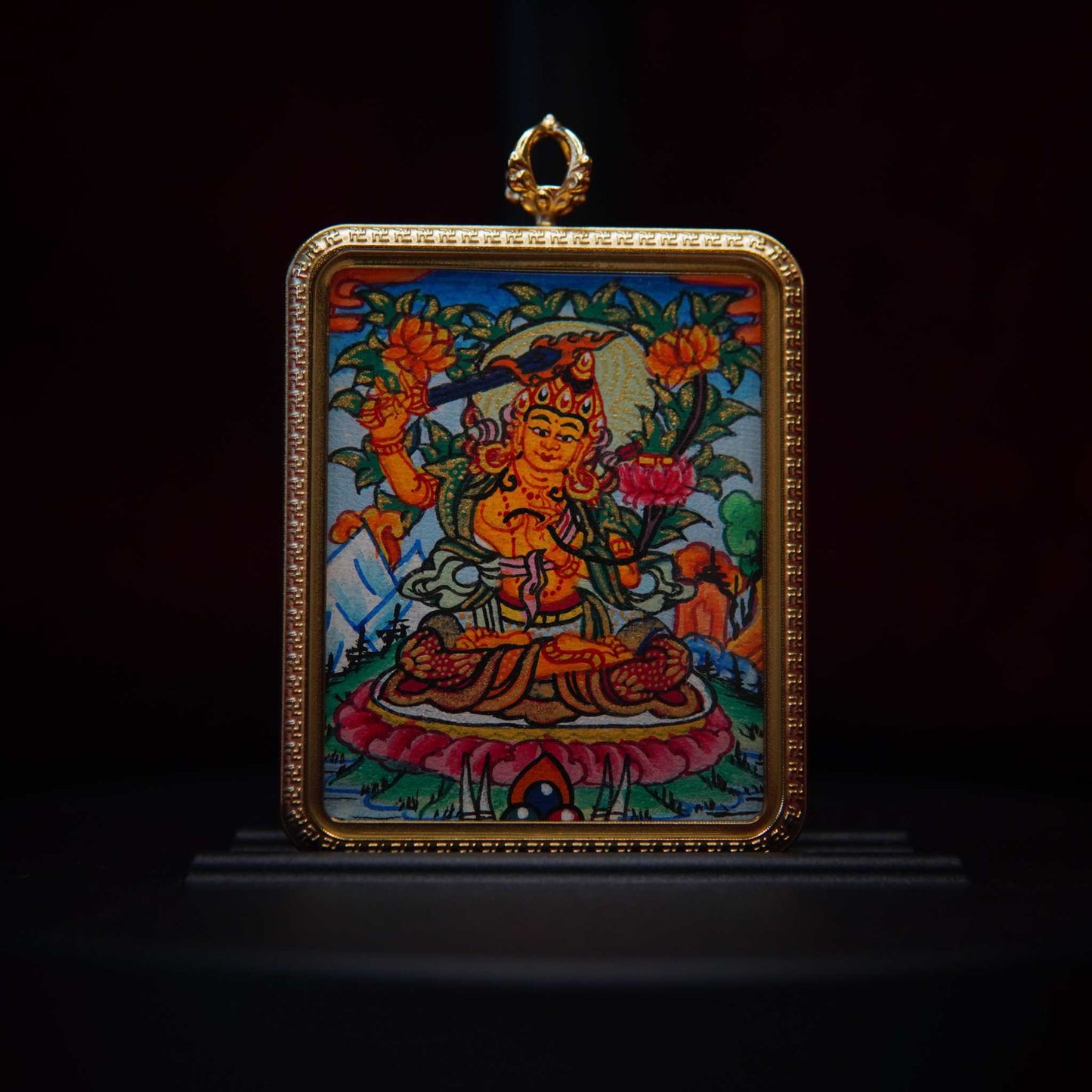 Hand-painted Manjushri necklace with vibrant Thangka art, featuring a gold-framed pendant showcasing the wisdom deity on a celestial blue background.