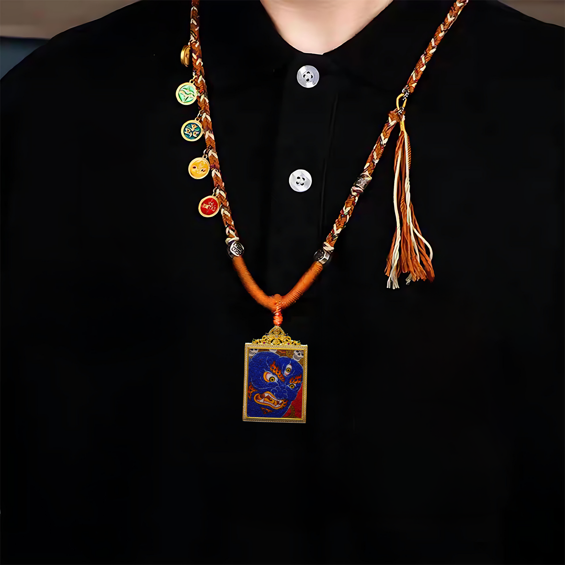 Mahakala Buddhist Pendant featuring fierce blue deity, skull crown, and golden flames on woven chain.